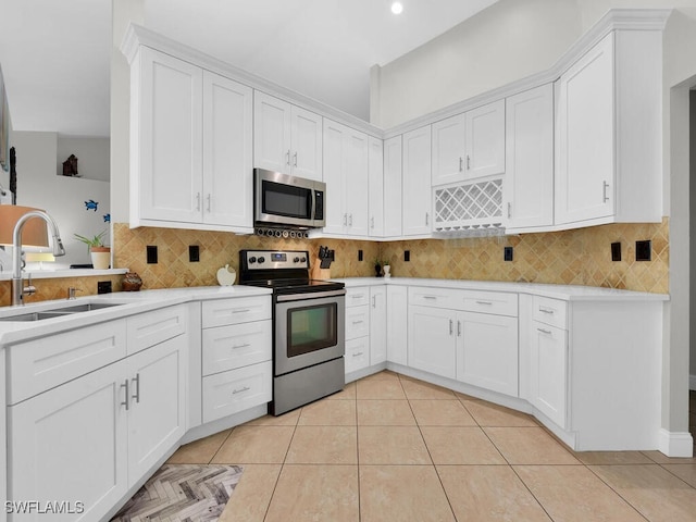 kitchen with stainless steel appliances, sink, light tile patterned floors, white cabinets, and decorative backsplash