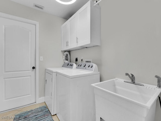 clothes washing area with washer and clothes dryer, cabinets, sink, and light tile patterned floors