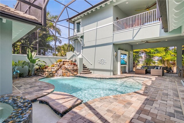 view of swimming pool featuring outdoor lounge area, pool water feature, a lanai, a patio, and ceiling fan