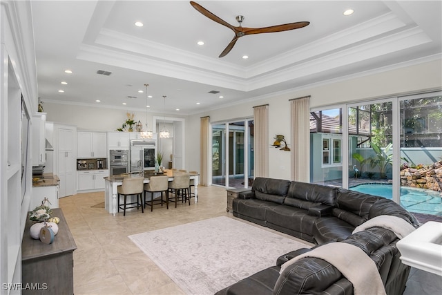 living room with crown molding, ceiling fan, and a raised ceiling