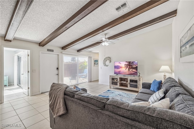 living room featuring ceiling fan, light tile patterned flooring, beamed ceiling, and a textured ceiling