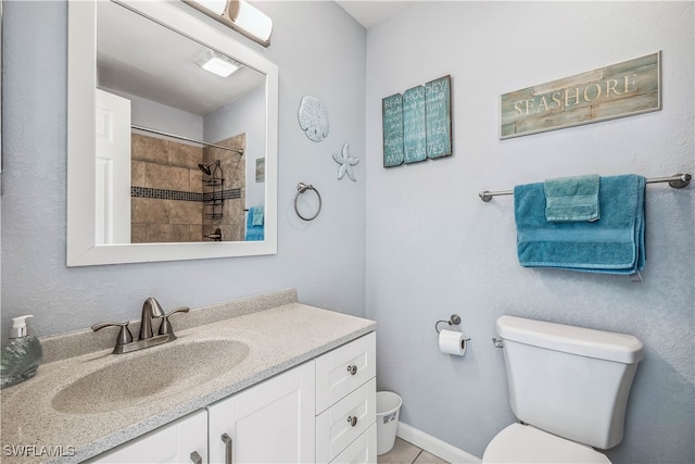 bathroom featuring toilet, vanity, tile patterned flooring, and a tile shower