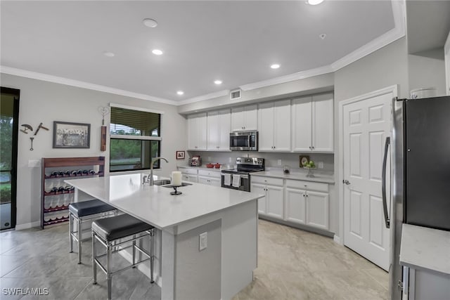 kitchen with stainless steel appliances, a breakfast bar, crown molding, white cabinetry, and a center island with sink