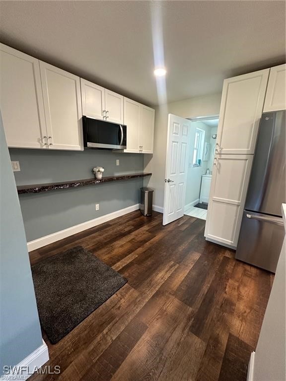 kitchen with white cabinetry, stainless steel appliances, washer / dryer, and dark hardwood / wood-style floors