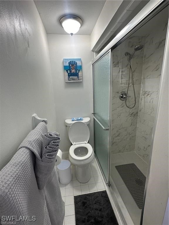 bathroom featuring toilet, tile patterned floors, and a shower with shower door