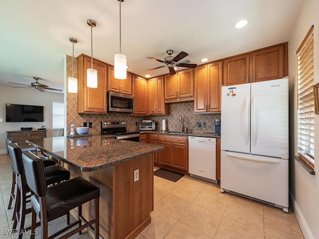 kitchen with ceiling fan, a breakfast bar area, sink, stainless steel appliances, and hanging light fixtures