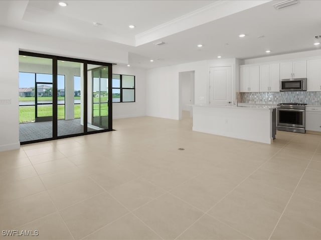 unfurnished living room featuring light tile patterned flooring and a tray ceiling