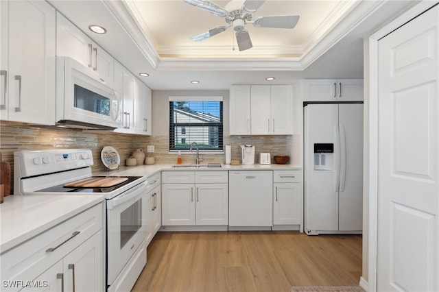 kitchen featuring white cabinets, a tray ceiling, and white appliances