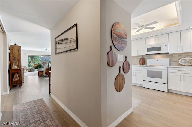 kitchen with white cabinets, light wood-type flooring, and white appliances