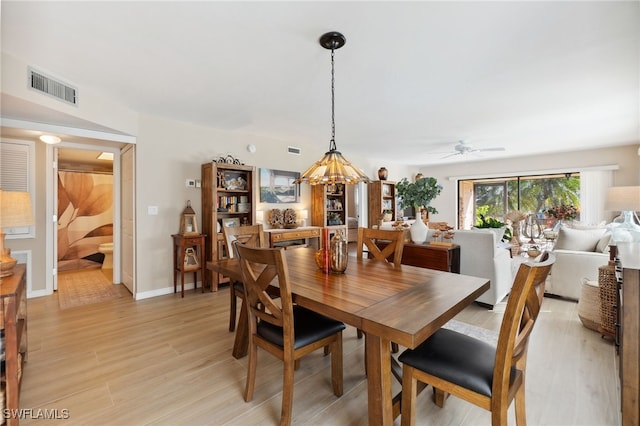 dining area featuring light hardwood / wood-style flooring and ceiling fan with notable chandelier