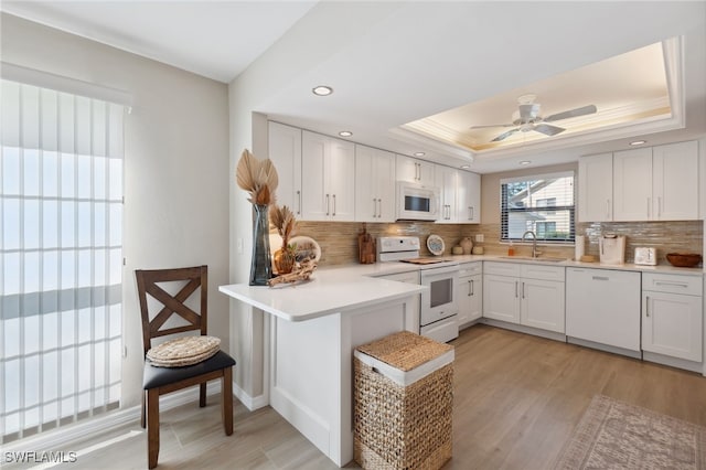 kitchen featuring sink, white cabinetry, kitchen peninsula, and white appliances