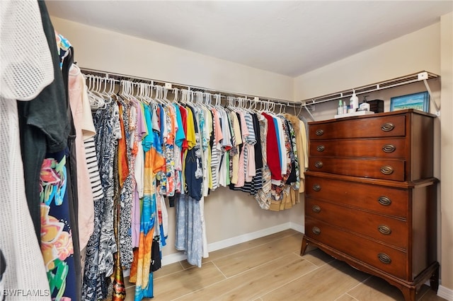 walk in closet with light hardwood / wood-style flooring