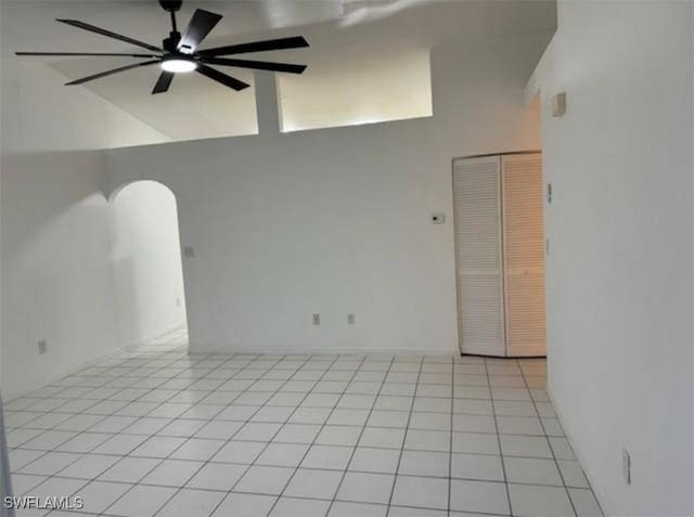 unfurnished room with ceiling fan, light tile patterned floors, and a towering ceiling