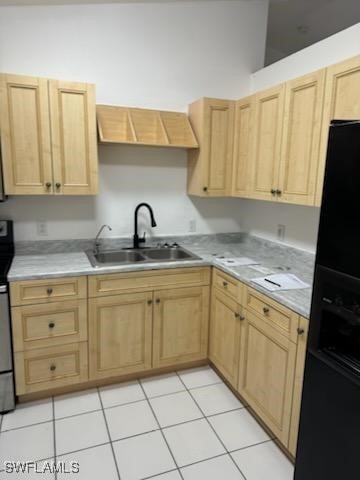 kitchen featuring black refrigerator, sink, light brown cabinets, stainless steel stove, and light tile patterned flooring