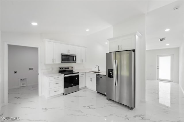 kitchen with sink, stainless steel appliances, white cabinetry, and vaulted ceiling