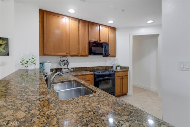 kitchen featuring sink, light tile patterned floors, black appliances, and dark stone counters