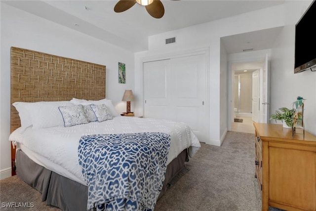 bedroom with a closet, ceiling fan, and light colored carpet