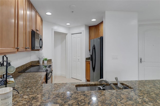 kitchen with stainless steel refrigerator with ice dispenser, sink, dark stone counters, range with electric stovetop, and light tile patterned flooring