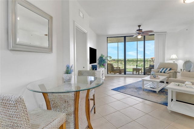 tiled living room with ceiling fan and a wall of windows