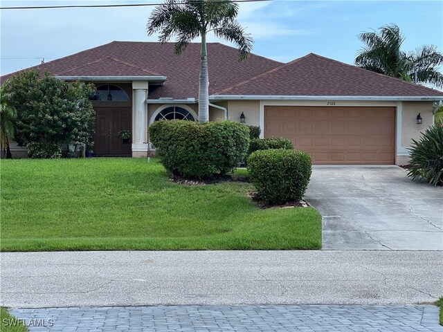 single story home with a garage and a front lawn