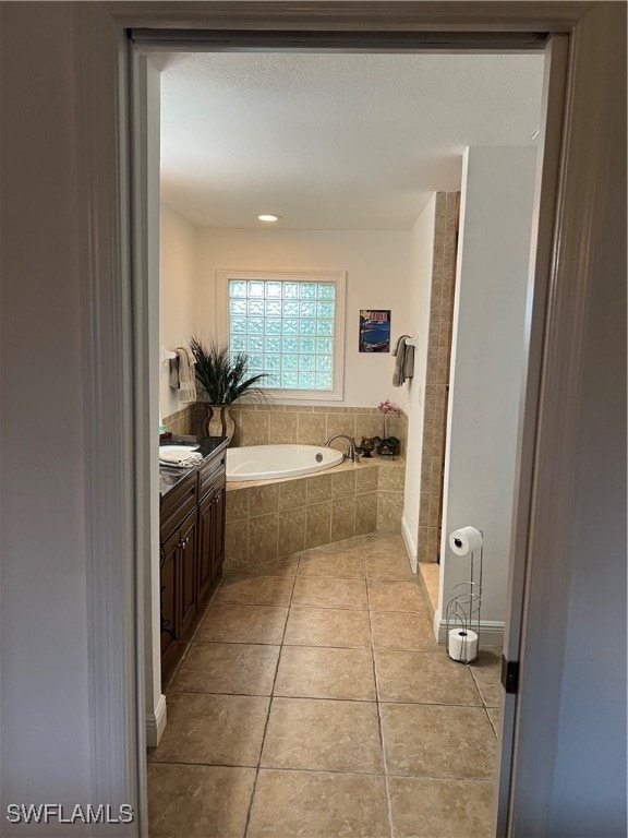 bathroom featuring tile patterned flooring, tiled tub, and vanity