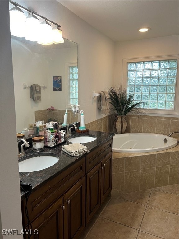 bathroom with tile patterned floors, a relaxing tiled tub, and vanity