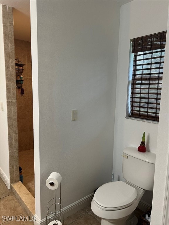 bathroom with tile patterned flooring, a tile shower, and toilet