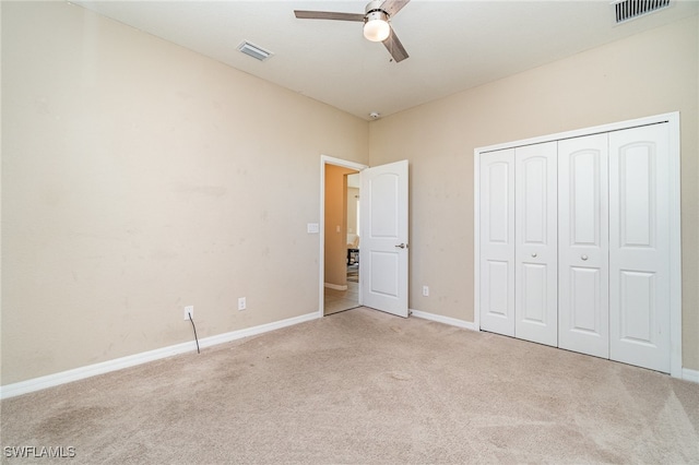 unfurnished bedroom featuring ceiling fan, light colored carpet, and a closet