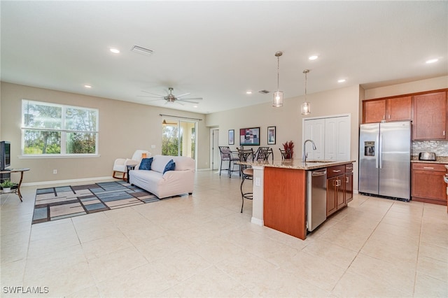 kitchen featuring a center island with sink, decorative light fixtures, appliances with stainless steel finishes, and a healthy amount of sunlight