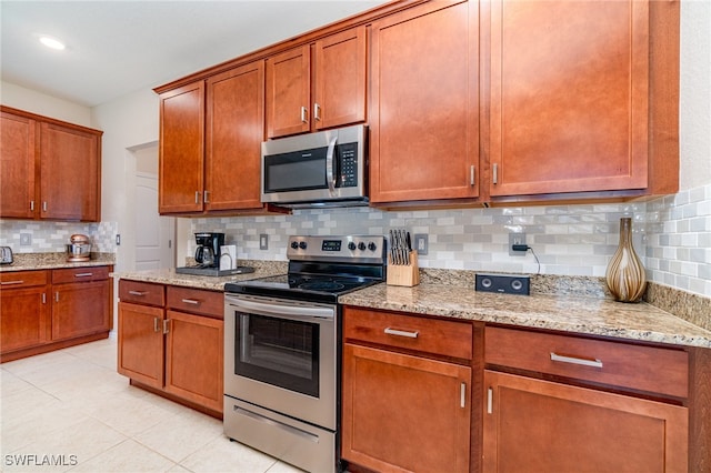 kitchen with decorative backsplash, appliances with stainless steel finishes, light stone counters, and light tile patterned floors