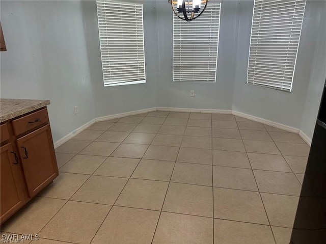 unfurnished dining area with light tile patterned flooring and a chandelier