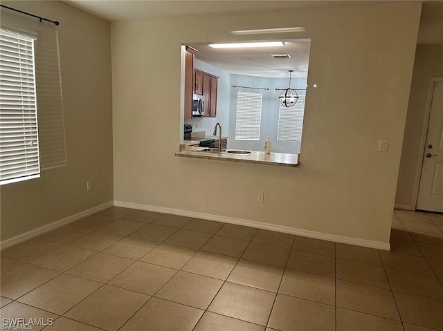 tiled empty room featuring a chandelier and sink