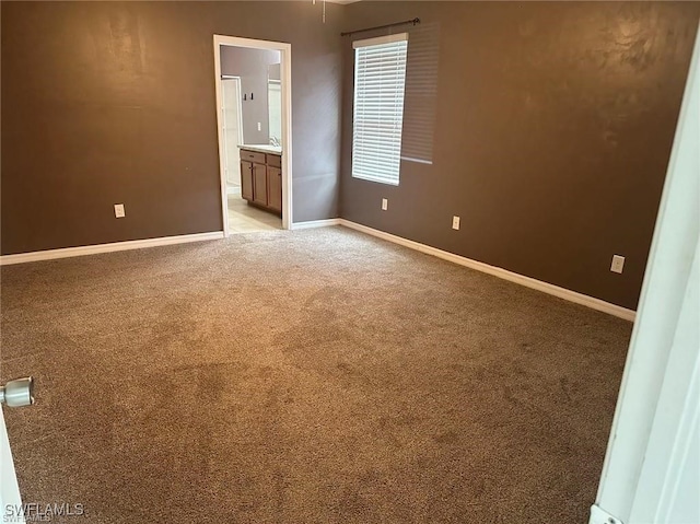 unfurnished bedroom with ensuite bathroom, sink, and light colored carpet