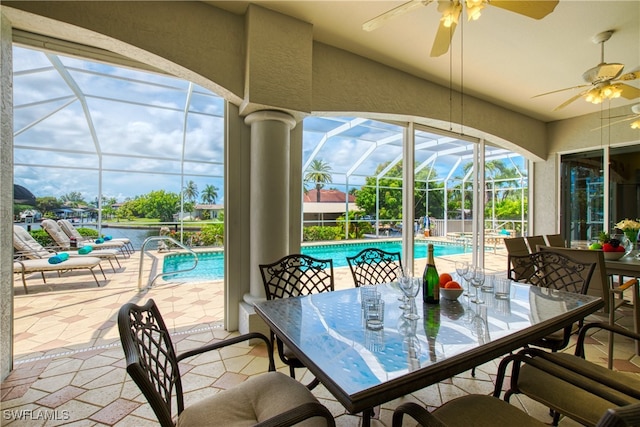 sunroom / solarium with ceiling fan and a water view