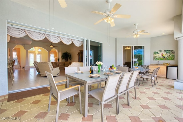 tiled dining room with ceiling fan, sink, and ornate columns