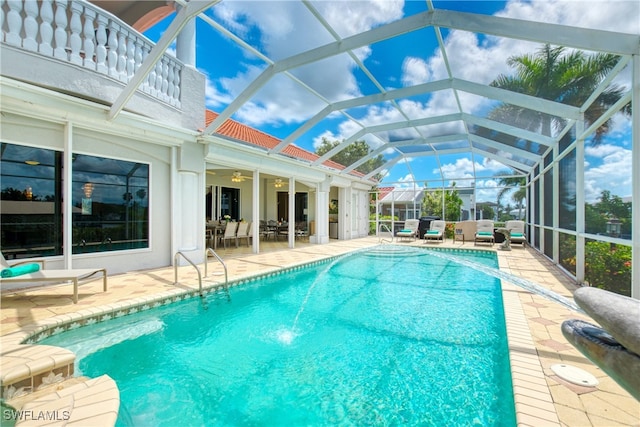 view of swimming pool with glass enclosure, ceiling fan, and a patio