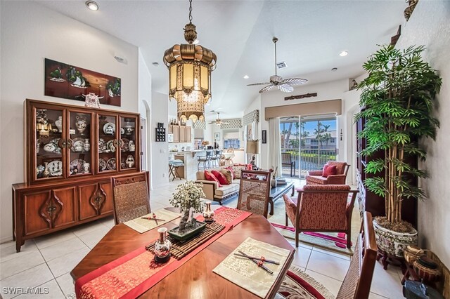 dining area featuring light tile patterned flooring, ceiling fan with notable chandelier, and vaulted ceiling