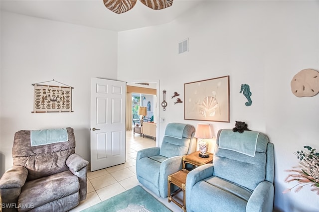 living area featuring ceiling fan, a towering ceiling, and light tile patterned floors