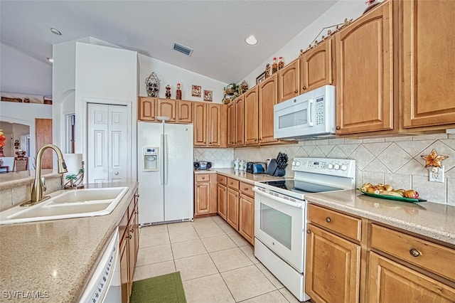 kitchen with lofted ceiling, light stone counters, light tile patterned floors, sink, and white appliances