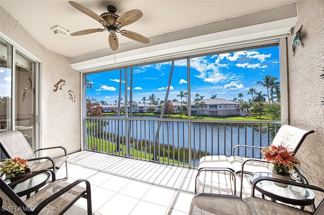 sunroom / solarium with a residential view, a water view, and ceiling fan