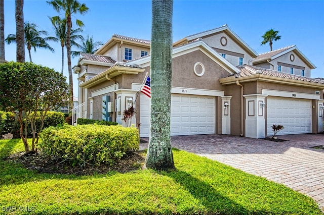 view of front facade featuring a tiled roof, decorative driveway, an attached garage, and stucco siding