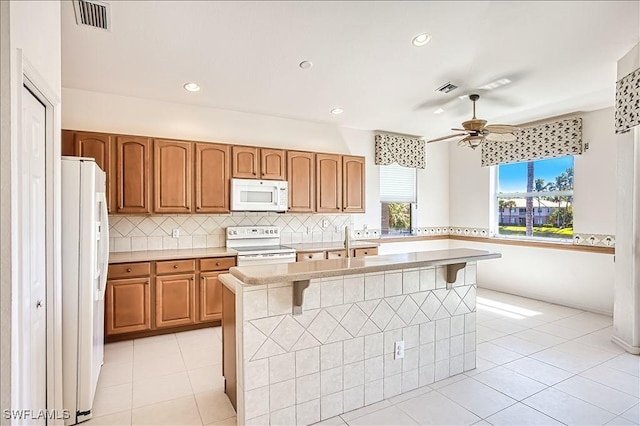 kitchen with light tile patterned floors, visible vents, backsplash, and white appliances