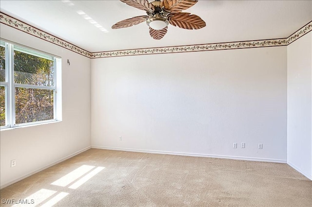 spare room with ceiling fan, baseboards, and light carpet