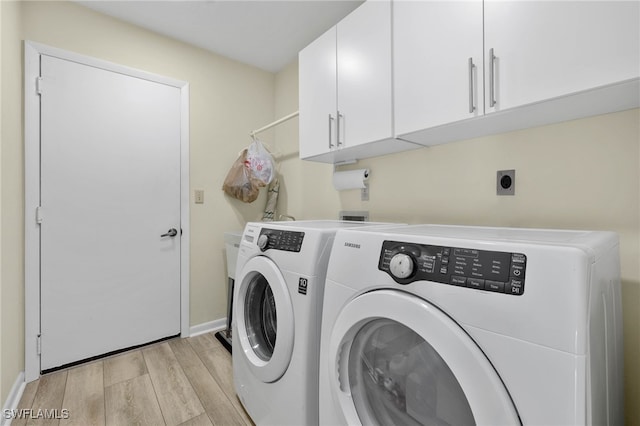 laundry room featuring washer and clothes dryer, light hardwood / wood-style flooring, and cabinets