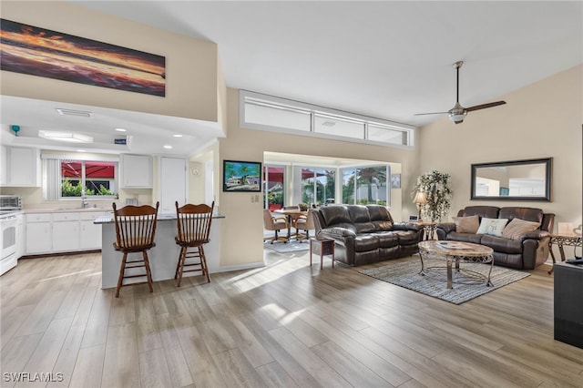 living room with light wood-type flooring, a wealth of natural light, and ceiling fan