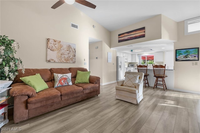 living room featuring ceiling fan, light hardwood / wood-style flooring, and high vaulted ceiling