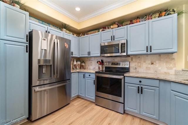 kitchen with appliances with stainless steel finishes, light stone countertops, ornamental molding, light hardwood / wood-style flooring, and backsplash