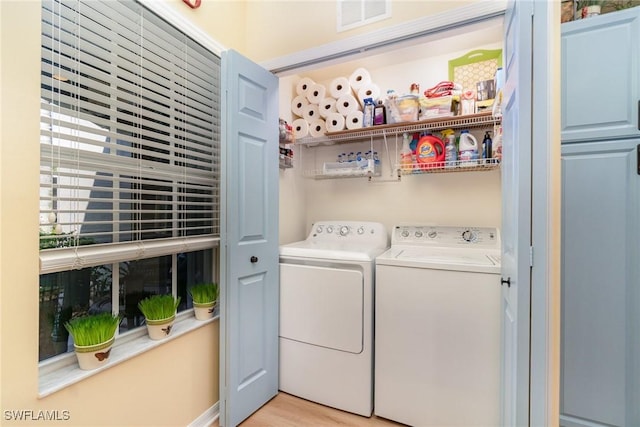 laundry area with light hardwood / wood-style floors and washer and clothes dryer