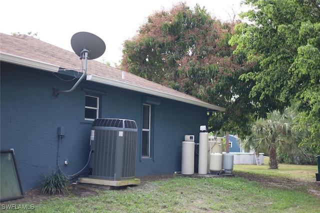 view of side of property with cooling unit and a lawn