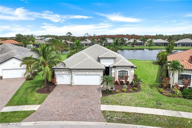 view of front of property featuring a front yard, a garage, and a water view